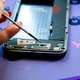 Una foto del retro del Fairphone 4 aperto con una persona che passa un cacciavite su una vite